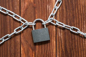 Padlock and chain on wooden background. Metal chain and locked padlock on wooden background. Safety concept