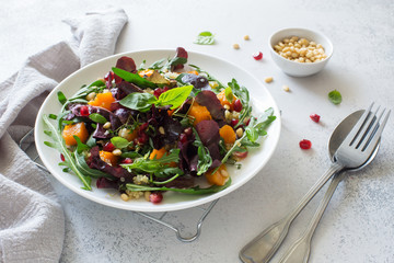 Fresh vegetable salad with pumpkin, greens and pine nuts