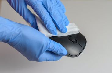 Woman with gloves cleaning and disinfecting computer mouse with napkins Corona virus cleaning and disinfection of your workspace from office and home . Stop the spread of coronavirus .