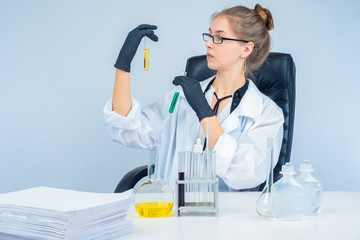 Work in a chemical laboratory. The girl is holding test tubes with colored chemical liquids. Testing of product samples. Laboratory quality control of raw materials.