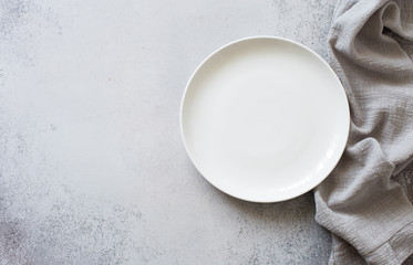 Obraz na płótnie Canvas White empty plate and linen napkin on a gray stone slate