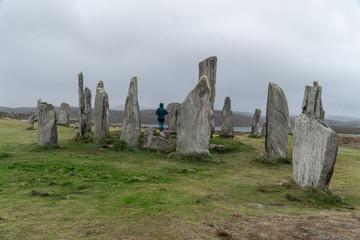 Girl, traveler stainding inside the Calanais Standing Stones in Outer Hebrides, Isle of Lewis, Scotland, UK. Moody and rainy weather.