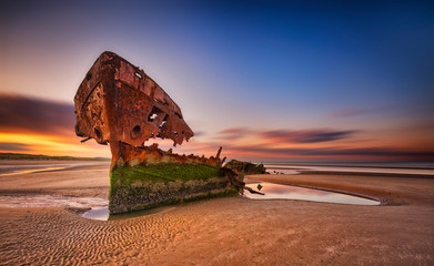 Baltray shipwrack,  Shipwrecked off the coast of Ireland, An  shipwreck or abandoned shipwreck,,boat Wreck Sunset light at the beach, Wrecked boat abandoned stand on beach or Shipwrecked off the coast