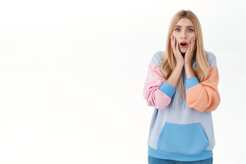 Portrait of concerned blond girl gasping worried, looking at person telling bad news, express compassion and feeling sorry for friend stuck in trouble, standing white background insecure