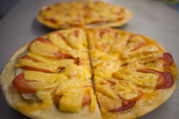 two round pizzas with different fillings, cut in half with cheese, salami with mushrooms and tomatoes