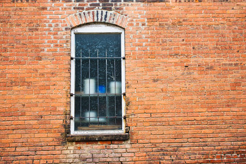 Brick wall with window with old crock type pots on shelf 
