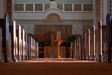 medium wide shot of an empty church sanctuary with afternoon sunlight pouring in creating shadows down the aisle to the front of the church 