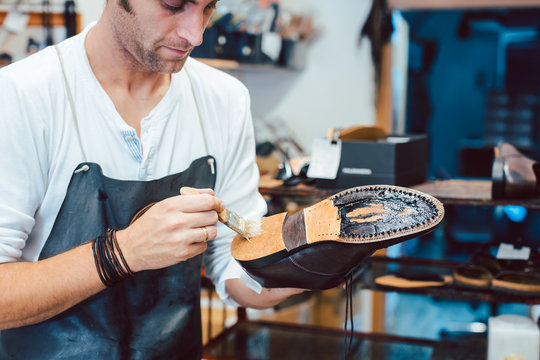 Shoemaker putting glue on sole of a shoe