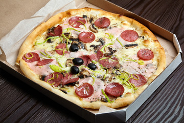 Pizza in a cardboard box on wooden table