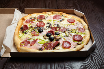 Pizza in a cardboard box on wooden table