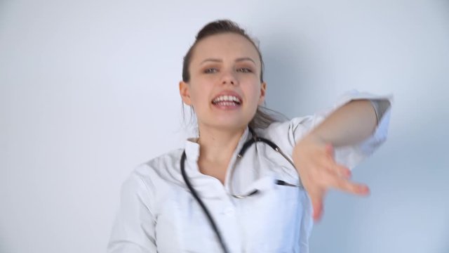 Funny doctor woman in a white coat with a stethoscope dancing and celebrates victory over coronavirus covid-19 in a hospital