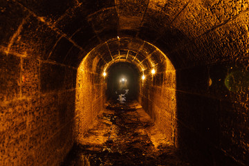 Old vaulted flooded round underground drainage sewer tunnel with dirty sewage water