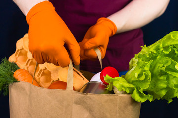 Delivery man wearing protective gloves holds paper bag with food