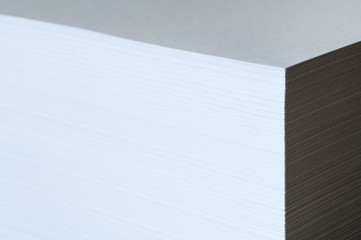 Studio photo of multiple sheets of A4 paper stack (ream) on black background. Simple, isolated object with copy space perfect for illustrating various concepts. Selective focus (shallow DOF).