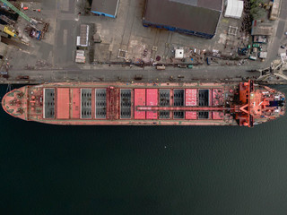 Aerial drone photo. TOP DOWN. Bulk vessel during loading operation in Port of Gdańsk, Poland. Bulker is a merchant ship specially designed to transport unpackaged bulk cargo.