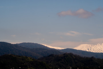 View of the foothills of the Caucasus. District of the city of Batumi. At the high peaks lies snow. On the lower mountains are residential buildings. The terrain has a different color.