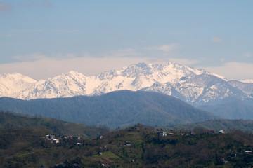View of the foothills of the Caucasus. District of the city of Batumi. At the high peaks lies snow. On the lower mountains are residential buildings. The terrain has a different color.