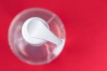 Container with alcohol gel on the red background