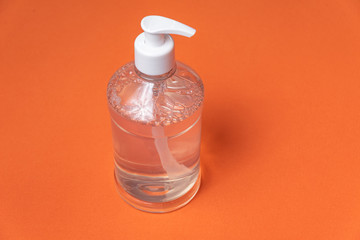 Container with alcohol gel on the orange background