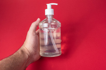 Man hand in container with alcohol gel on the red background