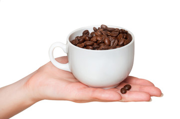 Grains of coffee in a white cup. Female hand holds a cup with coffee beans on a white background. Sweet dessert.