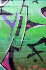 Abstract colorful fragment of graffiti paintings on old brick wall in green colors. Street art...