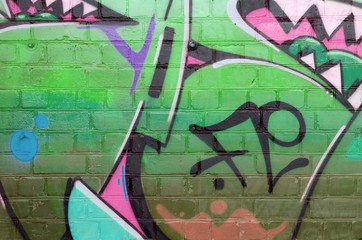 Abstract colorful fragment of graffiti paintings on old brick wall in pink and green colors. Street...