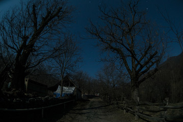 Full moon over quiet village at night. Beautiful night landscape of old town street with lights