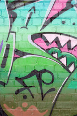 Abstract colorful fragment of graffiti paintings on old brick wall in green colors. Street art...