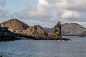 Beautiful coastline with sharp conical rocky bluffs, blue water and puffy gray and white clouds
