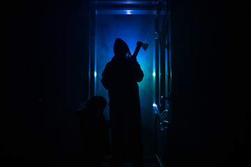 Silhouette of an unknown shadow figure on a door through a closed glass door. The silhouette of a human in front of a window at night. Scary scene halloween concept of blurred silhouette of maniac.