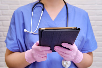 A nurse in a blue uniform holds a tablet during quarantine . A doctor with a stethoscope remotely helps via the Internet.