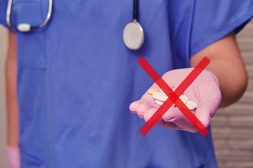 Hand in medical glove with a handful of crossed out pills under ban, closeup