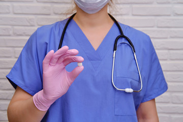 Tablet in the doctor hand, close-up. A nurse in protective gloves holds one tablet