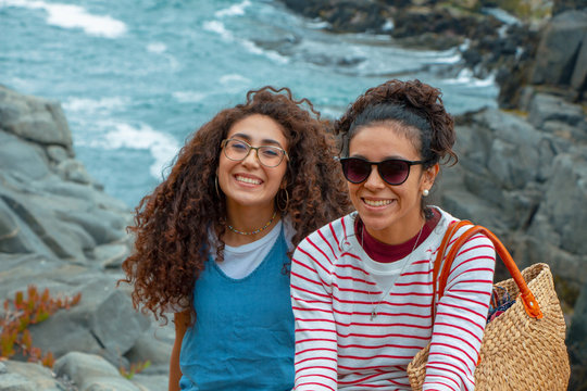 Dos muchachas que se rien en frente de un roquer&iacute;o en la playa