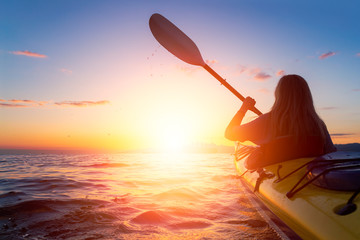 Woman on a sea kayak is paddling in the ocean during a colorful and vibrant sunset. Taken in Jericho, Vancouver, British Columbia, Canada. Concept: Adventure, Holiday, Vacation, Lifestyle, Freedom © edb3_16