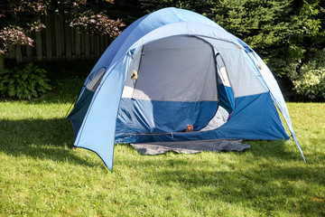 Boys foot sticking out of a blue tent in a backyard.