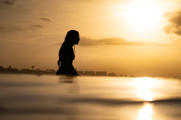 silhouette of a woman surfing in the ocean