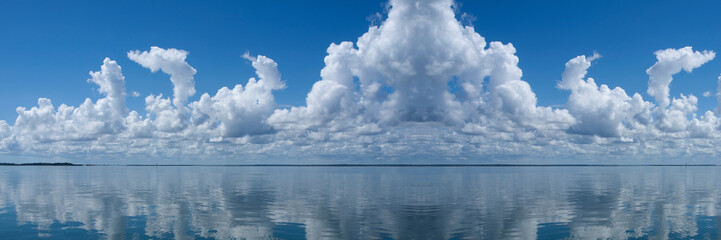 Naklejka na ściany i meble Atmospheric sky art image. White Cumulonimbus cloud in blue sky with ocean water reflections. Australia.