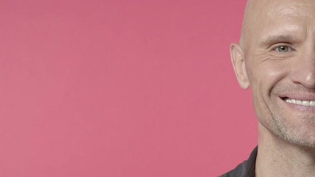 Close-up half-face of handsome elderly bald guy with bristle, middle-aged man look camera and showing beaming smile, express happiness and overjoy, laughing cheerful, pink background