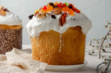 Kulich Easter cake with eggs with white glaze on white wooden background with willow