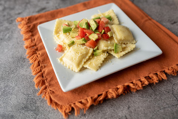 Creative cheese ravioli topped with fresh tomato and avocado and seasoning.  Italian ravioli with a twist. 
