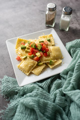 Creative cheese ravioli topped with fresh tomato and avocado and seasoning.  Italian ravioli with a twist. 