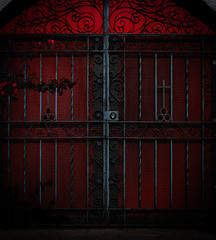 Dramatic, scary photo of old red church door locked in with black gate