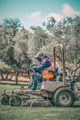 Man wear safety masks as a precaution after outbreak the Covid 19 during mows the grass with lawn...