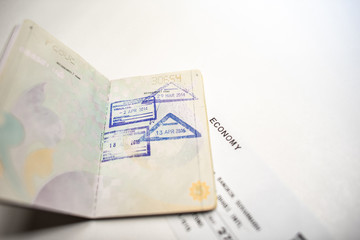 immigration stamps on passport and Thai passport with Plane economy ticket background.