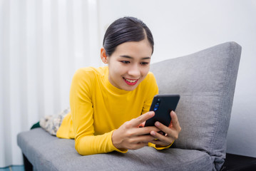 Young Asian woman watching series from online stream movie service with on demand video (VOD) website on smart device screen , After break from the effects of Coronavirus Covid-19.