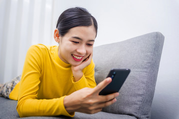 Young Asian woman watching series from online stream movie service with on demand video (VOD) website on smart device screen , After break from the effects of Coronavirus Covid-19.