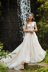 Obraz premium portrait of a young bride on the background of a waterfall