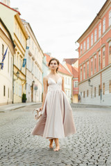 Obraz premium A young girl walks in a pink dress barefoot along the street in Prague